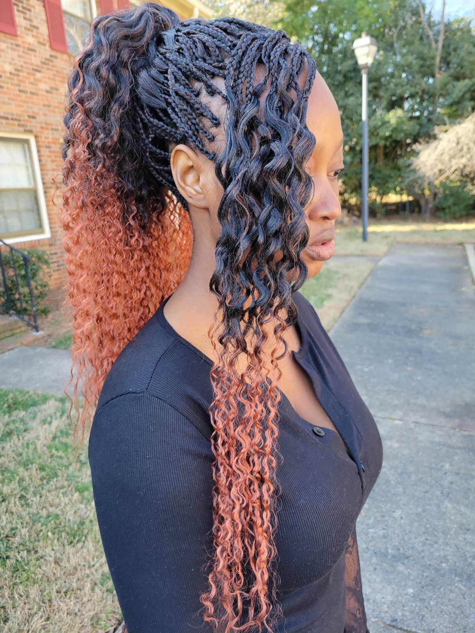 Micro braids in black with copper ombre curly ends, worn loose, side view