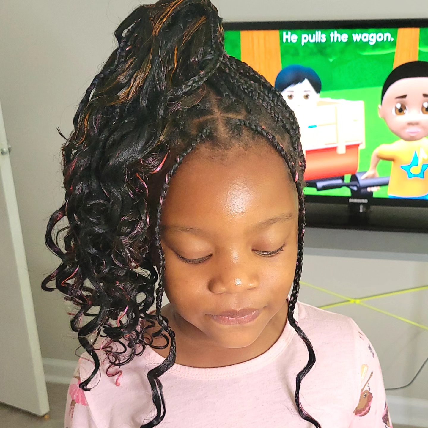 Kids boho braids with curly ends styled in a high ponytail on a young girl, side view