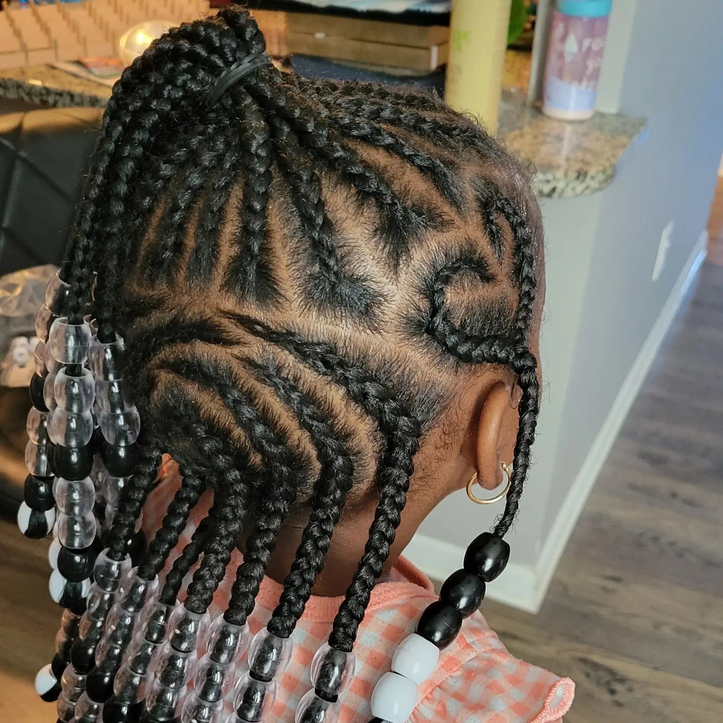 Kids braids with clear, black and white beads on a young girl, side view