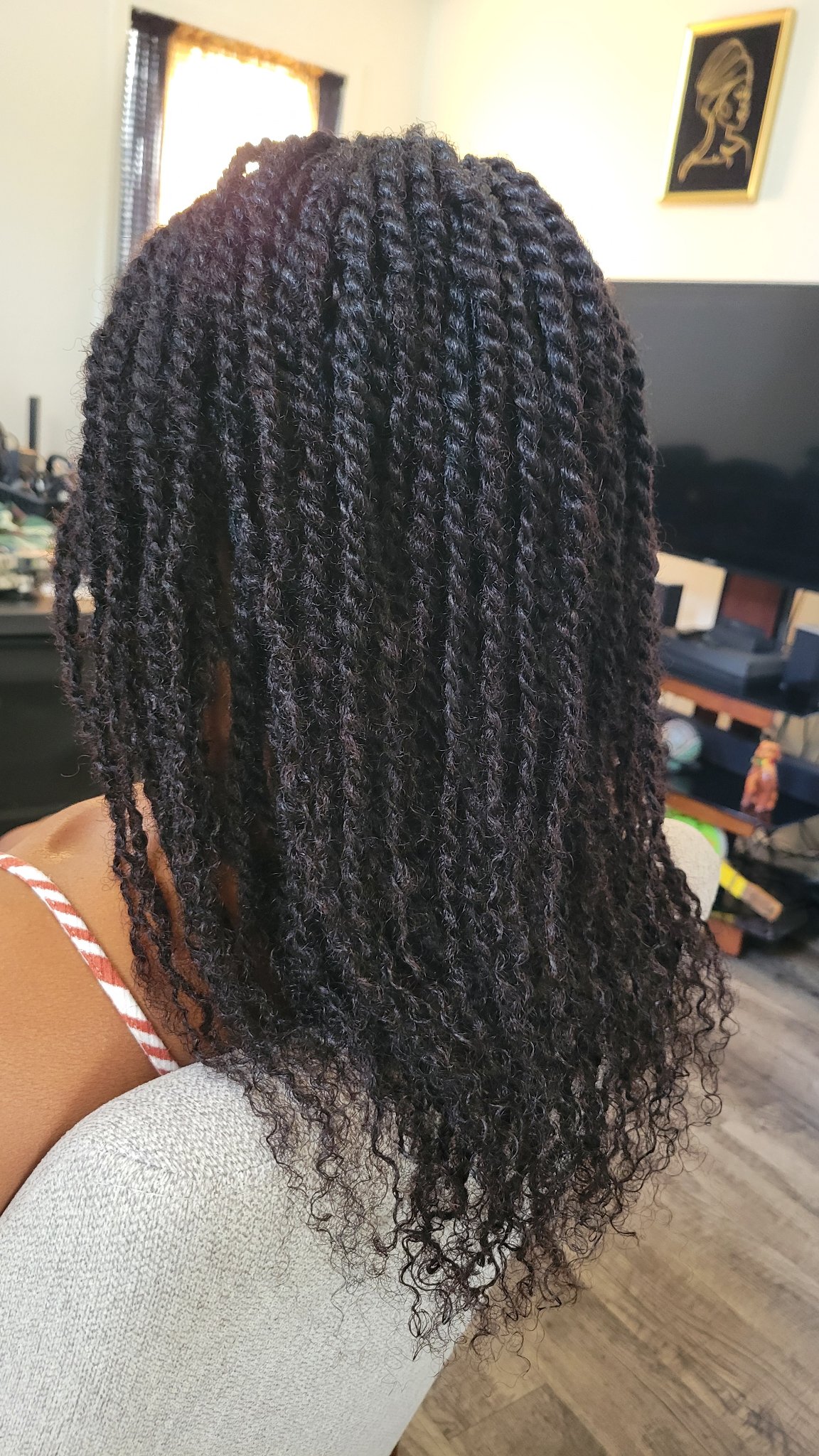 Black twists with curly ends seen from behind in the salon