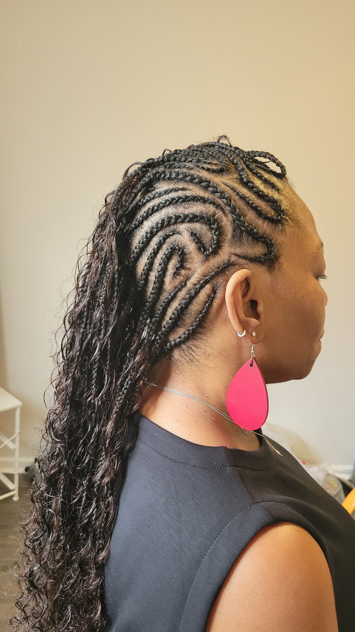 Feed-in cornrows with a swirl pattern flowing into long curly hair, right side profile view