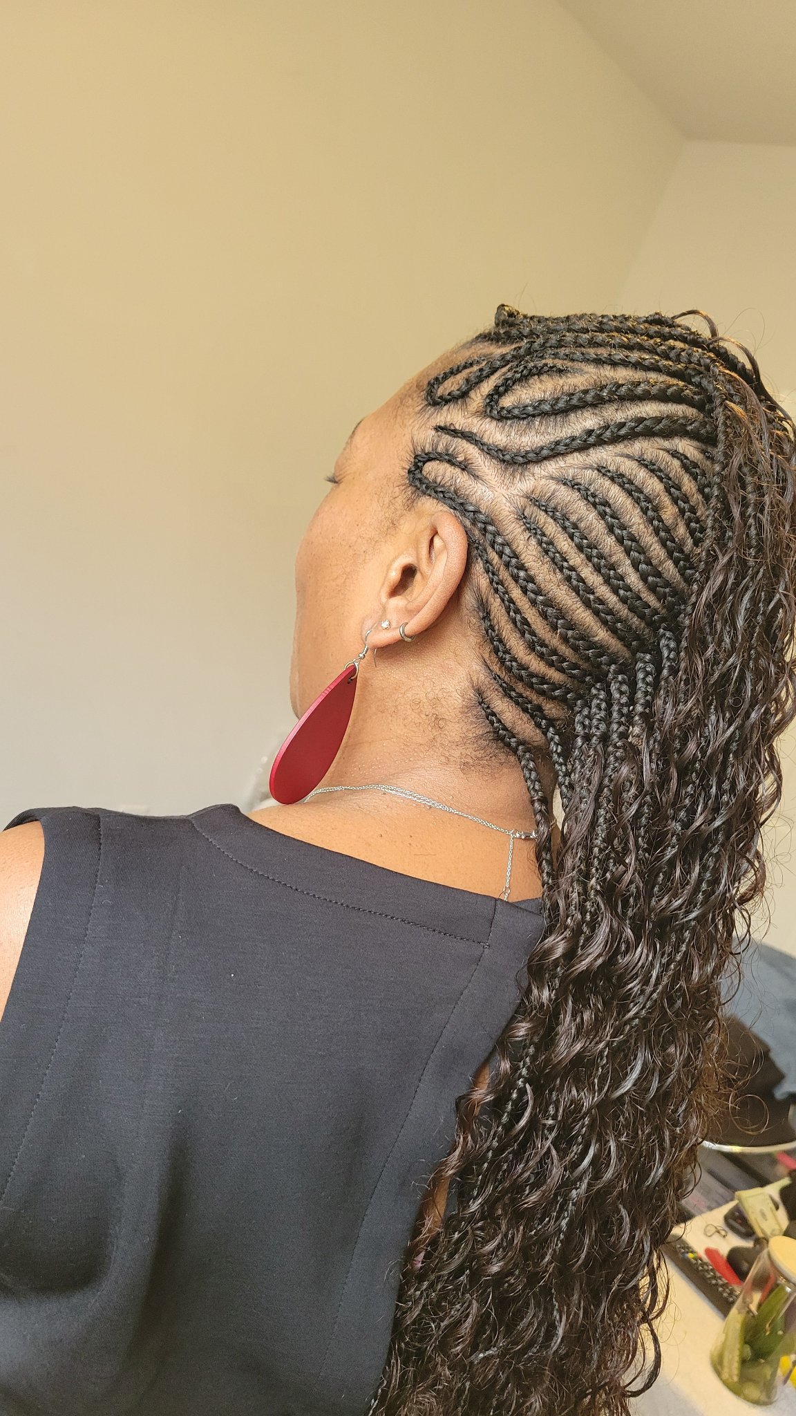 Feed-in cornrows with a swirl pattern flowing into long curly hair, left side profile view