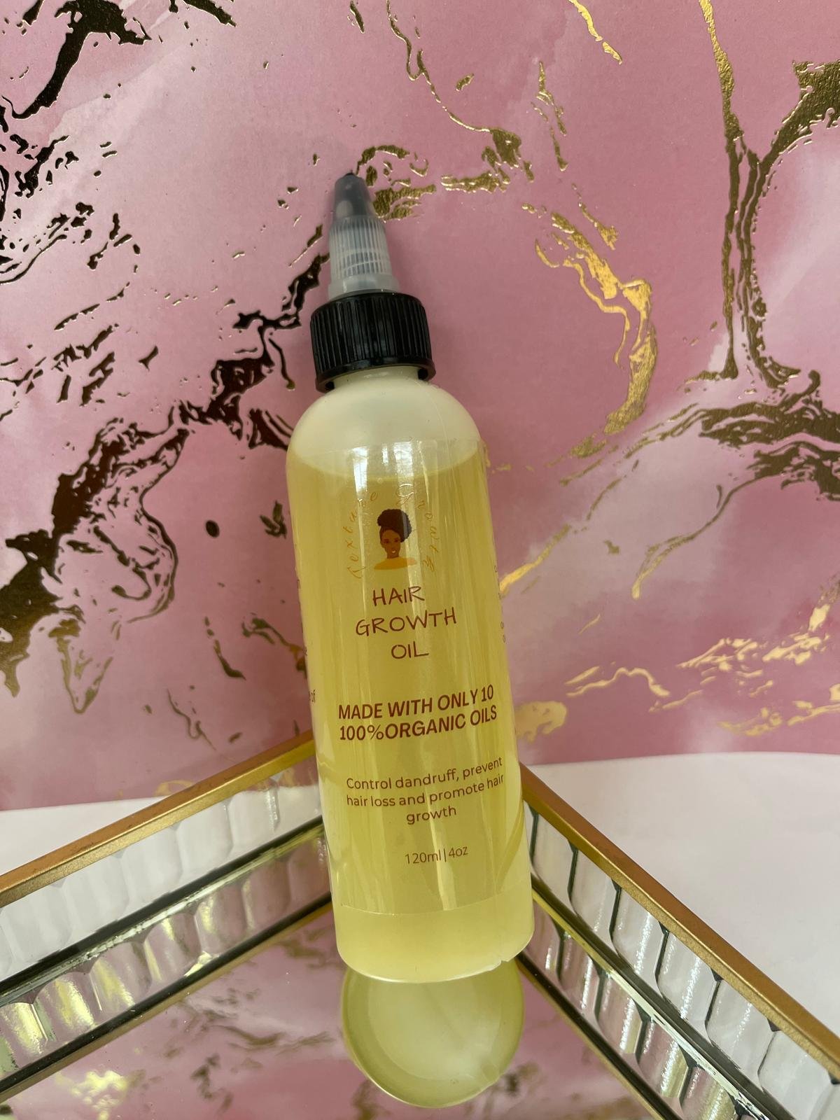 Texture Growth Hair Growth Oil bottle on a mirrored gold tray against a pink and gold marble backdrop
